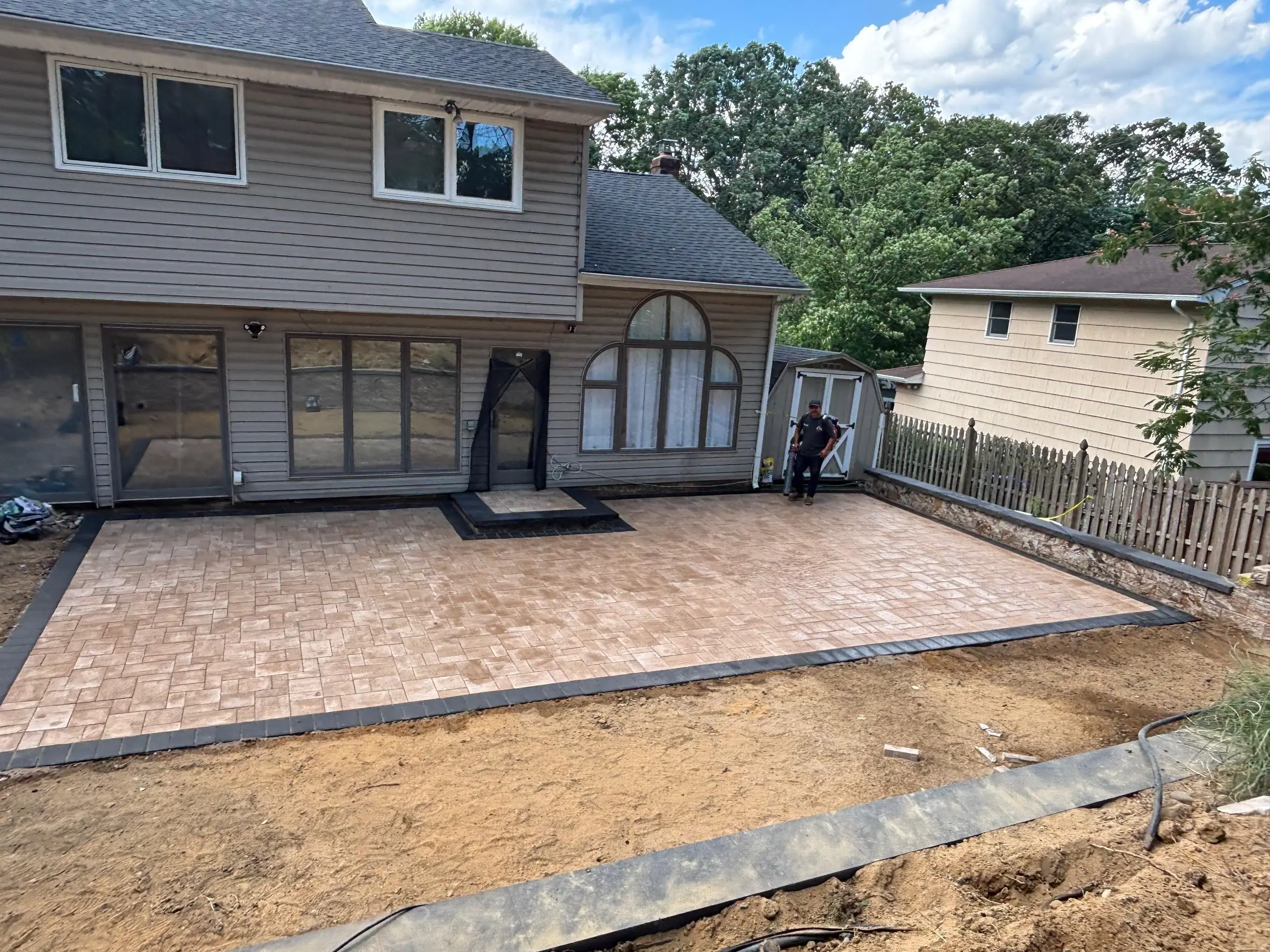 Large paver patio with a dark border installed by JCM Construction