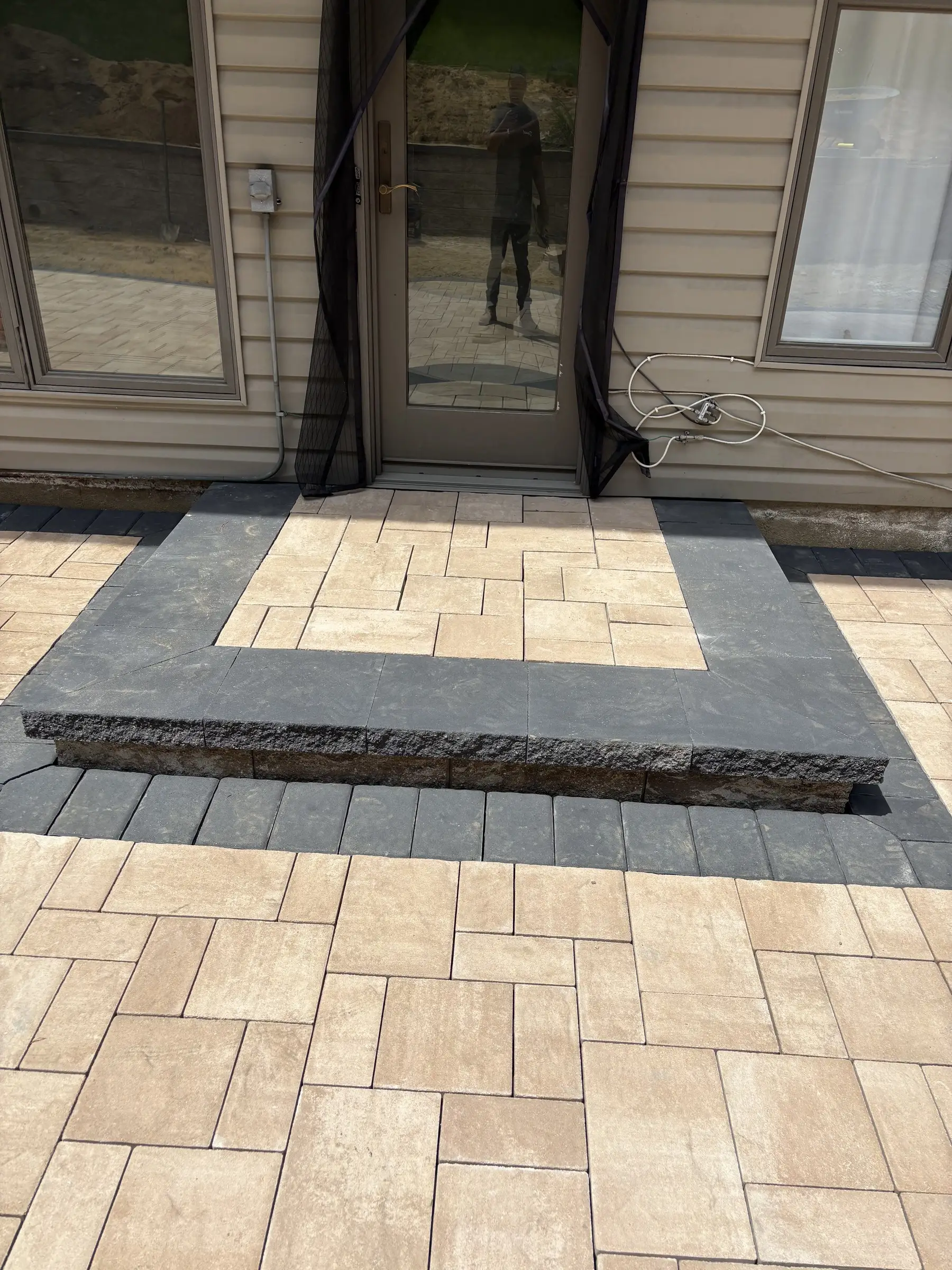 Paver patio with a dark stone border at the back door