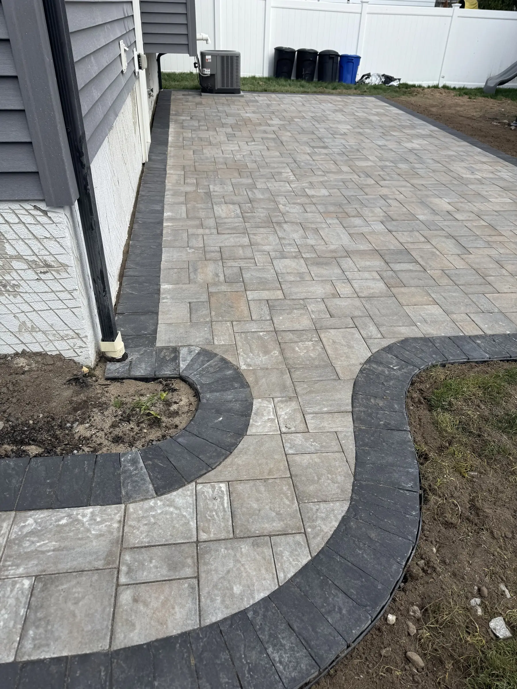 Gray paver patio with a curved dark border