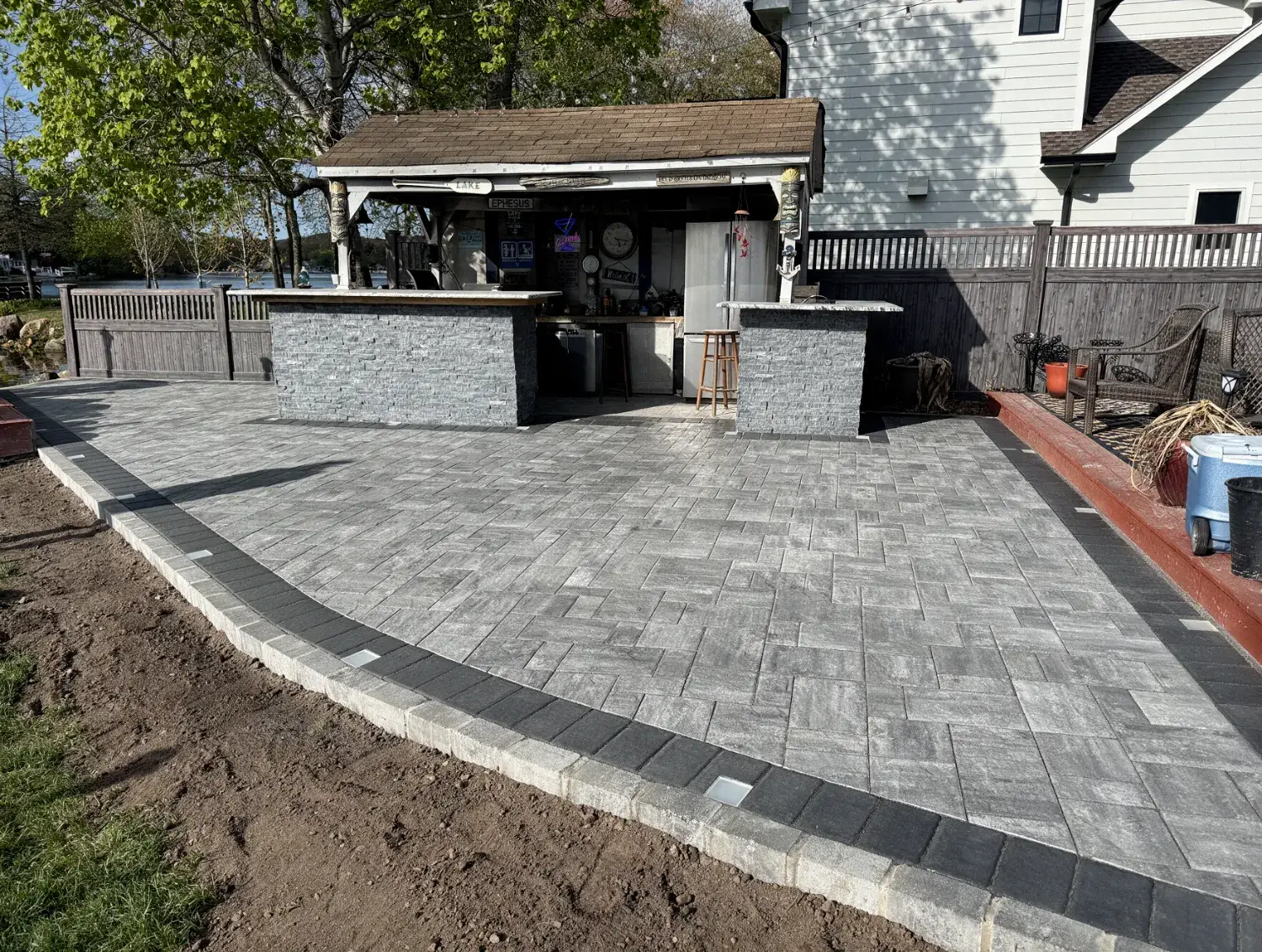 Large gray paver patio with a dark border and a stone outdoor bar