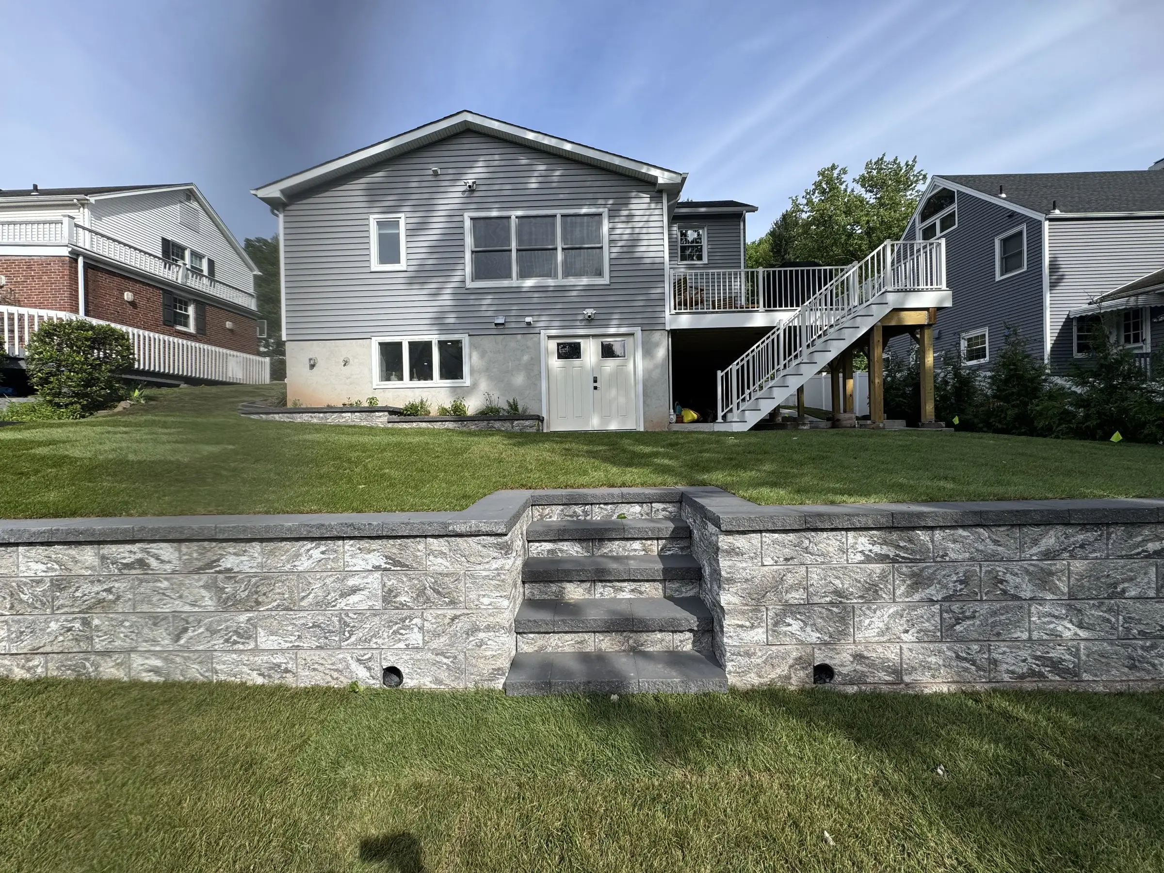 Stone retaining wall with built-in steps in a Northern New Jersey backyard
