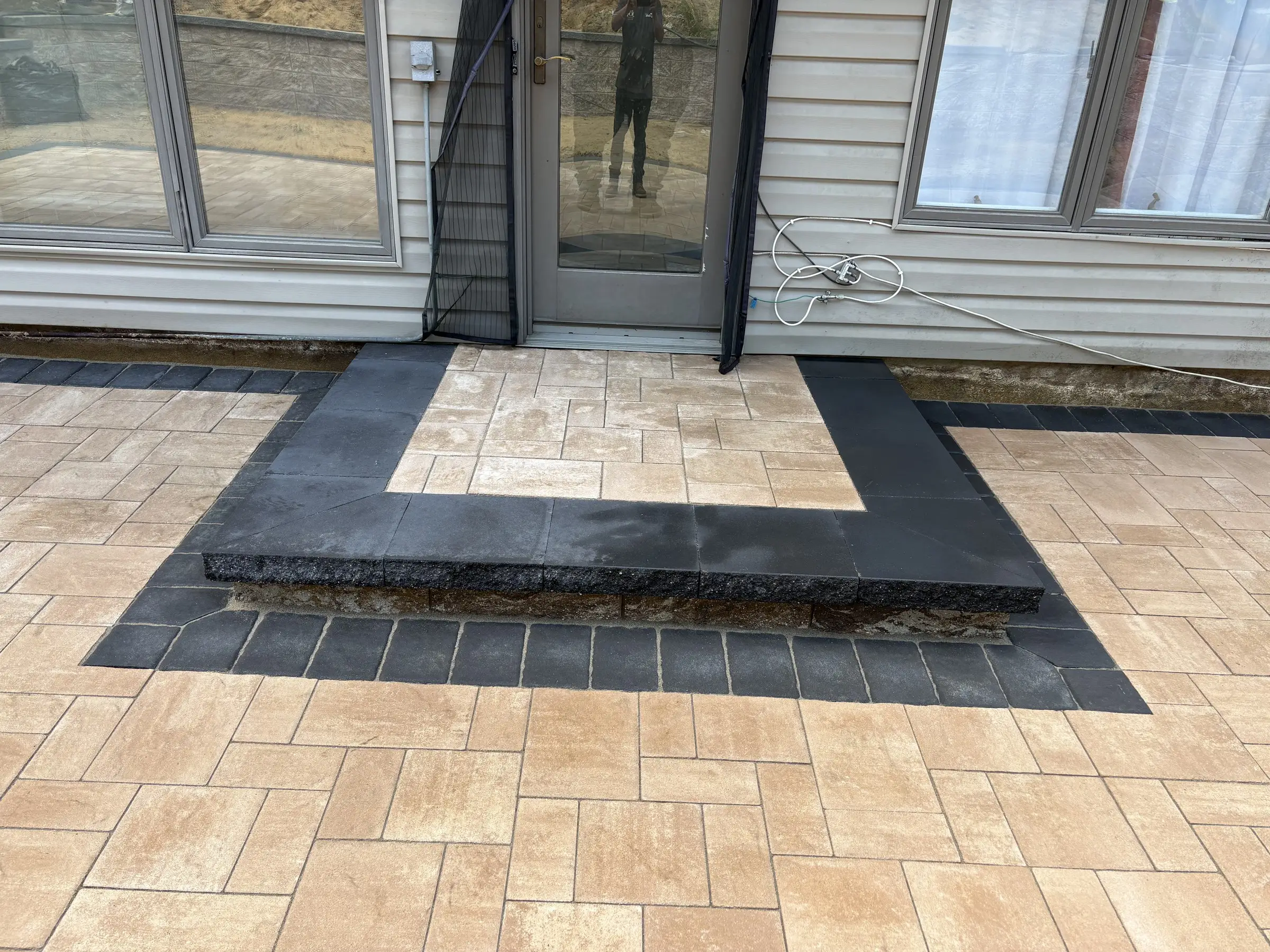 Tan paver patio with a dark border and step
